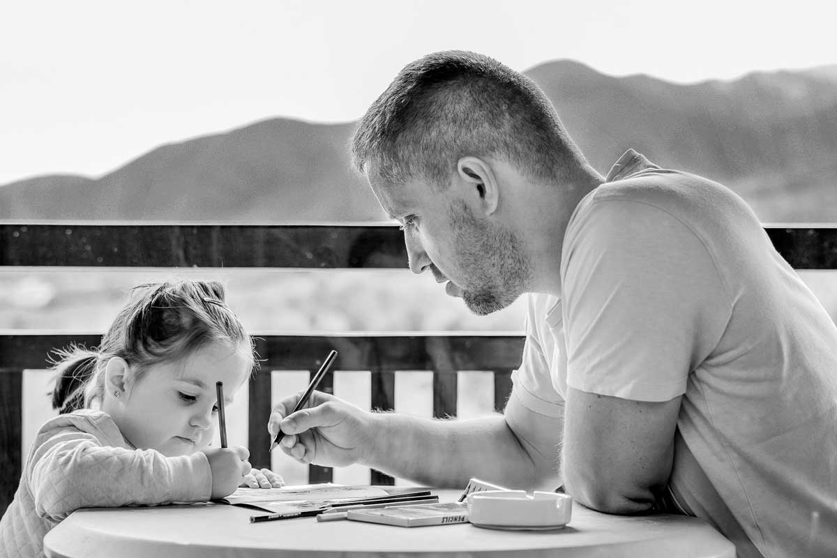 Padre y hija con un lápiz en la mano y escribiendo sobre una mesa