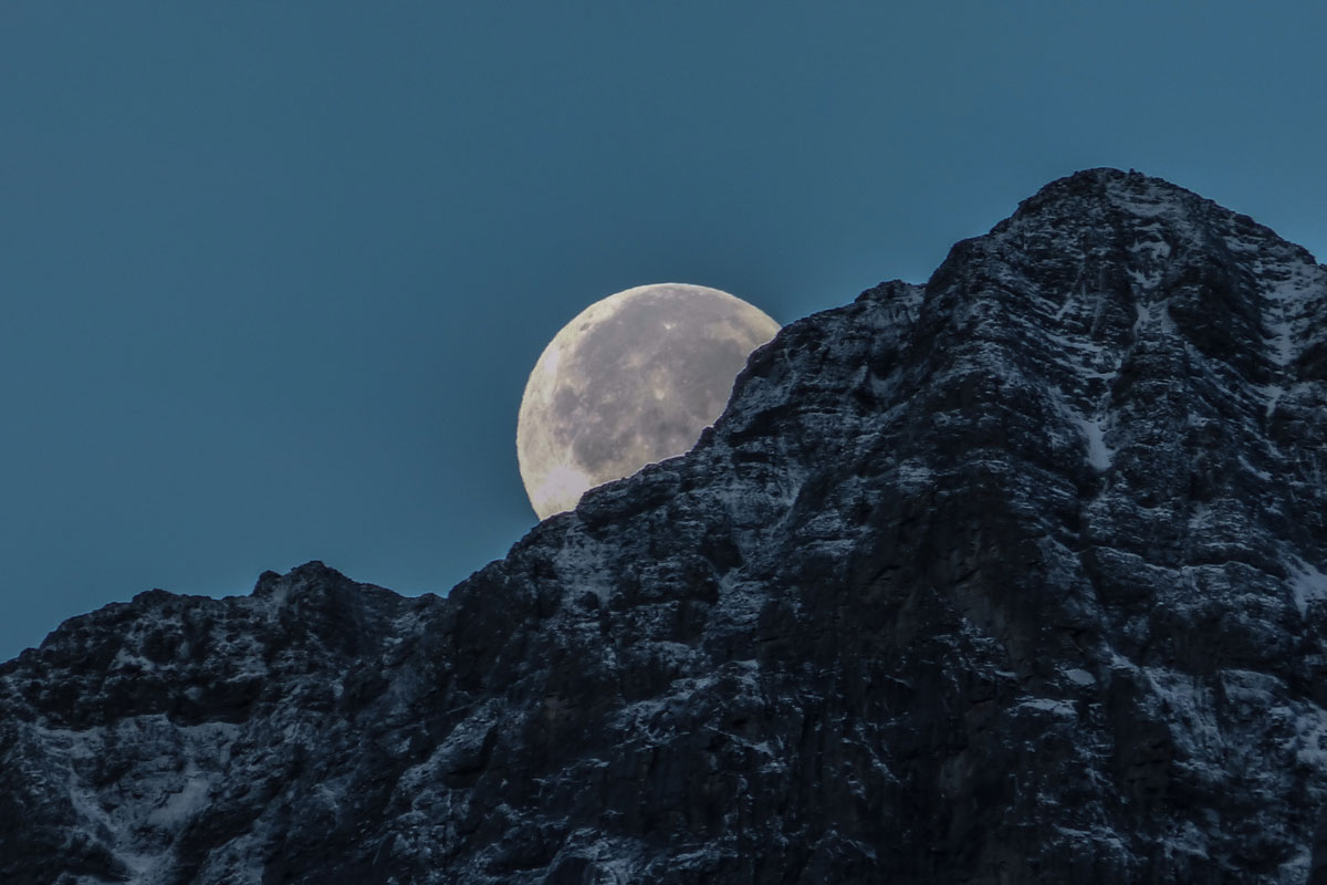 Luna apareciendo detrás de una montaña